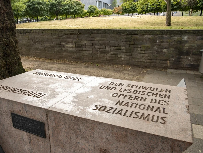 Rosa Winkel Memorial Steinernes Mahnmal in Köln mit Aufschrift für schwule und lesbische NS-Opfer vor Baum.Stone memorial in Cologne with inscription for gay and lesbian victims of National Socialism in front of tree.