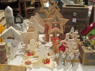 Handgefertigte Holzdekoration mit Sternen, Engeln und Weihnachtsmotiven auf Basartisch.