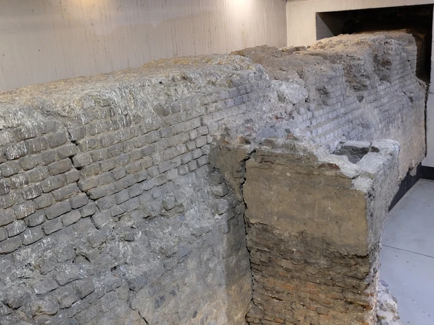 Roman city wall The picture shows a historic brick wall in a deep, illuminated underground parking garage.