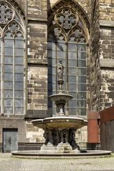 Petrusbrunnen Der Petrusbrunnen steht vor dem gotischen Kölner Dom mit detailreichen Spitzbögen und Fenstern.