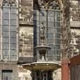 St. Peter's Fountain Der Petrusbrunnen steht vor dem gotischen Kölner Dom mit detailreichen Spitzbögen und Fenstern.The Petrusbrunnen stands in front of the Gothic Cologne Cathedral with its detailed pointed arches and windows.