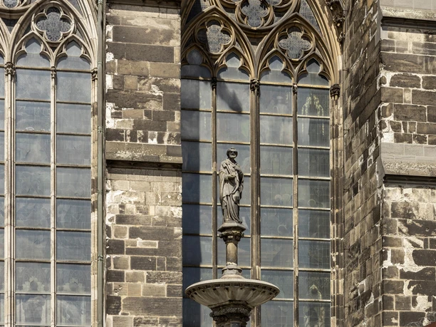 St. Peter's Fountain The Petrusbrunnen stands in front of the Gothic Cologne Cathedral with its detailed pointed arches and windows.