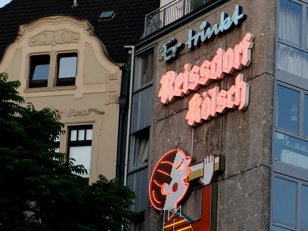 Reissdorf Leuchtreklame Leuchtende Reissdorf Kölsch-Werbung an urbanem Gebäude in Köln, voller traditioneller Braukunst.