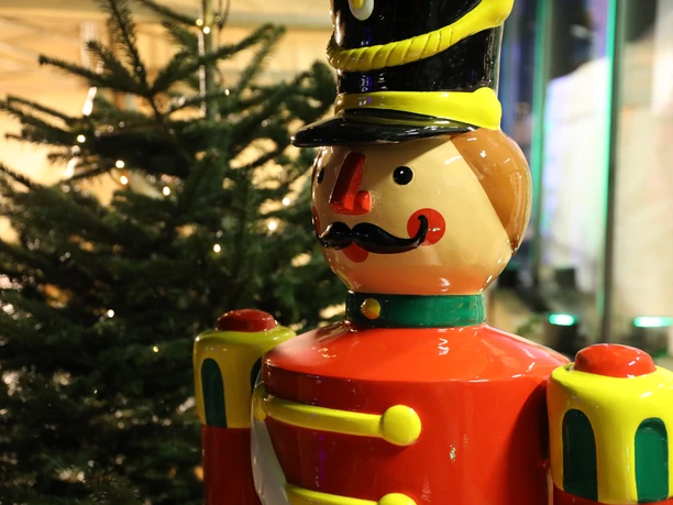 Weihnachtsmarkt Schloss Eulenbroich Nussknackerfigur in Uniform neben einem geschmückten Weihnachtsbaum, festliche Dekoration.