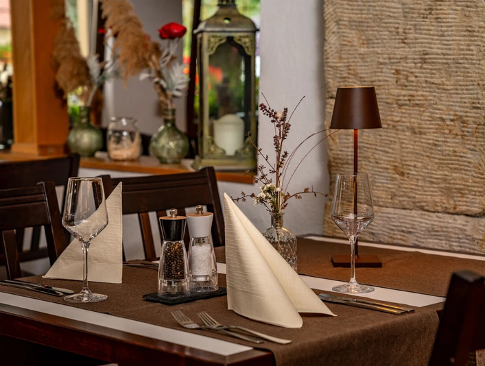Eleganter Restauranttisch mit brauner Tischdecke, zwei Weingläsern, gefalteten Servietten, Salz- und Pfefferstreuern sowie einer kleinen Tischlampe.Elegant restaurant table with brown tablecloth, two wine glasses, folded napkins, salt and pepper shakers and a small table lamp.Elegantní restaurační stůl s hnědým ubrusem, dvěma sklenicemi na víno, složenými ubrousky, solničkou a pepřenkou a malou stolní lampou.Elegancki stół restauracyjny z brązowym obrusem, dwoma kieliszkami do wina, złożonymi serwetkami, solniczką i pieprzniczką oraz małą lampką stołową.Elegante restauranttafel met bruin tafelkleed, twee wijnglazen, gevouwen servetten, peper- en zoutstel en een kleine tafellamp.Elegante tavolo da ristorante con tovaglia marrone, due bicchieri da vino, tovaglioli ripiegati, saliere e pepe e una piccola lampada da tavolo.