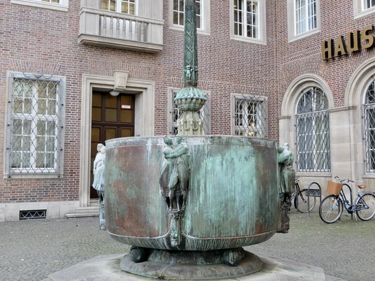 Fastnachtsbrunnen Fastnachtsbrunnen vor dem historischen Gebäude in Köln, mit bogenförmigen Figuren und Brunnenbecken.Carnival fountain in front of the historic building in Cologne, with arched figures and fountain basin.
