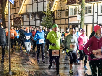 Christkindlauf Wiedenbrück Läufer in Winterkleidung nehmen abends an einem Stadtlauf teil; Schnee fällt leicht.