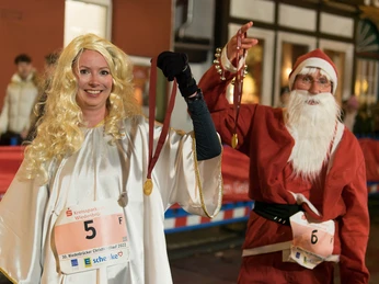 Christkindllauf Wiedenbrück Zwei verkleidete Personen als Christkind und Nikolaus mit Startnummern und Medaillen bei einem Lauf.