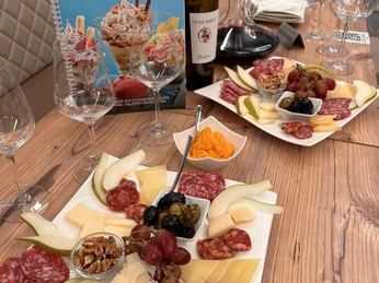 Eiscafé Smile Wein Tasting Platten mit Käse, Wurst, Nüssen, Obst und Wein auf einem Holztisch in einem Restaurant.