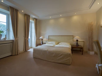 Ententurm Zimmer 2 Gemütliches Hotelzimmer mit Doppelbett, zwei Nachttischen, warmem Licht und großen Fenstern.