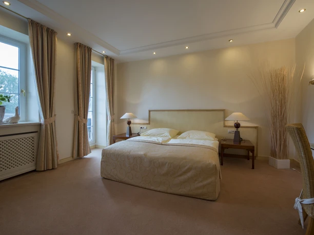 Ententurm Zimmer 2 Gemütliches Hotelzimmer mit Doppelbett, zwei Nachttischen, warmem Licht und großen Fenstern.