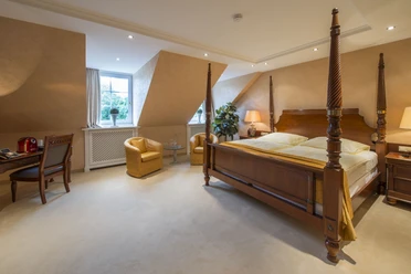 Ententurm Zimmer Luxuriöses Hotelzimmer mit Baldachinbett, Sitzbereich, Schreibtisch und traditionellem Dekor.