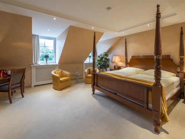 Ententurm Zimmer Luxuriöses Hotelzimmer mit Baldachinbett, Sitzbereich, Schreibtisch und traditionellem Dekor.