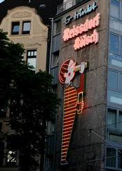 Reissdorf Leuchtreklame Neonreklame am Kölner Gebäude zeigt das ikonische Reissdorf-Kölsch-Logo, umgeben von Architektur.
