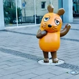 Maus Statue Die Maus-Statue mit erhobenem Arm, ein Symbol der beliebten Kindersendung, steht auf Gehwegplatten vor einem modernen Gebäude in Köln.The mouse statue with raised arm, a symbol of the popular children's show, stands on paving slabs in front of a modern building in Cologne.