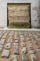 Römische Hafenstraße Römische Pflastersteine einer antiken Straße vor einer historischen Backsteinmauer in Köln.
