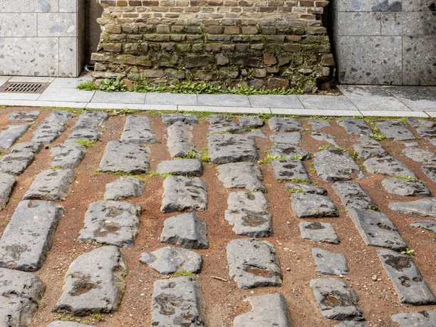 Römische Hafenstraße Römische Pflastersteine einer antiken Straße vor einer historischen Backsteinmauer in Köln.