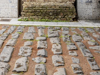 Roman harbor road Römische Pflastersteine einer antiken Straße vor einer historischen Backsteinmauer in Köln.Roman paving stones from an ancient street in front of a historic brick wall in Cologne.