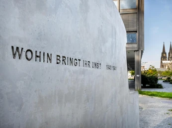 Monument to the gray buses Das Bild zeigt ein Industriedenkmal in Form von "grauen Bussen", eine eindringliche Erinnerung an die tragischen Ereignisse der NS-Zeit. Im Hintergrund ist der Kölner Dom sichtbar. Auf der Betonwand ist die Inschrift "Wohin bringt ihr uns? 1940/1941" zu sehen, die eine tief bewegende Frage stellt. The picture shows an industrial monument in the form of "gray buses", a haunting reminder of the tragic events of the Nazi era. Cologne Cathedral is visible in the background. The inscription "Where are you taking us? 1940/1941" can be seen on the concrete wall, posing a deeply moving question.