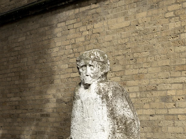 Johann Adam Schall von Bell Skulptur Die Skulptur zeigt Johann Adam Schall von Bell, gefertigt aus hellem Stein, mit markanten Gesichtszügen und imposantem Gewand, vor einer Mauer stehend.