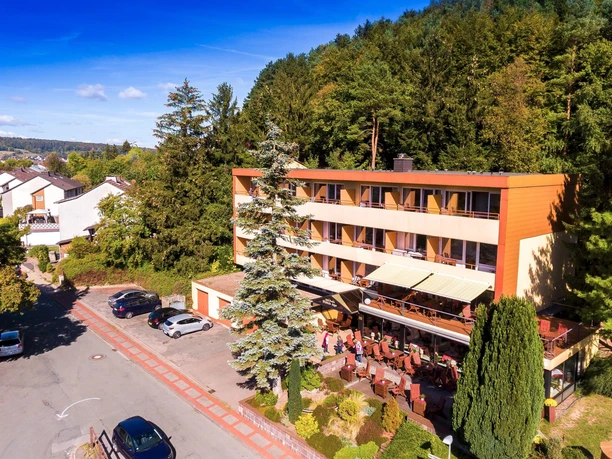 Hotel Waldcafe Jäger Bad Driburg_Komplettaufnahme_Avenarius Wohlfühlhotels_2500.jpg Hotel Waldcafe Jäger Bad Driburg umgeben von Bäumen mit Terrasse und angrenzendem Parkplatz