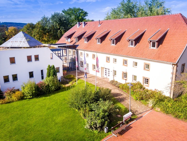 Hotel im Schlosspark_Willebadessen_Luftaufnachme _Avenarius Wohlfühlhotels.jpg Luftaufnahme eines historischen Gebäudes umgeben von gepflegten Grünflächen im Park.