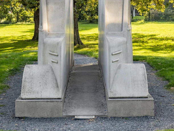 Monument to the gray buses Two massive gray concrete buses stand symbolically next to each other, surrounded by green lawns and trees in the background.