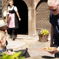 so-schmeckt-bad-zwischenahn-kostprobe-schinken-spieker.jpg Ein Mann serviert einem entspannten Paar im Freien traditionell belegte Ammerländer Schinkenplatte.A man serves a traditional Ammerland ham platter to a relaxed couple outdoors.En mand serverer en traditionel ammerlandsk skinketallerken for et afslappet par i det fri.Een man serveert een traditionele Ammerlandse hamschotel aan een ontspannen stel buiten.