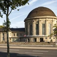Bahnhof KoelnMesse Deutz Historischer Empfangsbereich des Bahnhofs Köln Messe/Deutz mit markantem Kuppeldach unter blauem Himmel.Historic reception area of Cologne Messe/Deutz station with striking domed roof under a blue sky.