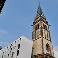 Christ Church Turm der Christuskirche in Köln bei klarem Himmel, links modernere Gebäude, im Hintergrund ein Sendeturm.Tower of the Christuskirche in Cologne with clear skies, modern buildings on the left, and a transmission tower in the background.