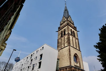 Christuskirche Turm der Christuskirche in Köln bei klarem Himmel, links modernere Gebäude, im Hintergrund ein Sendeturm.