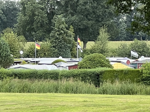 Campingplatz am Salingsloh Ein Campingplatz mit Wohnwagen und deutschem Flaggenschmuck, umgeben von viel Grün und Hecken.