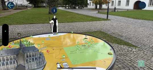 3D Landschaftsmodell Eine interaktive 3D-Landkarte mit Miniaturmodellen und Symbolen vor einem Klostergebäude.