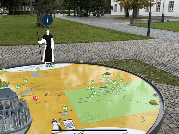 3D Landschaftsmodell Eine interaktive 3D-Landkarte mit Miniaturmodellen und Symbolen vor einem Klostergebäude.