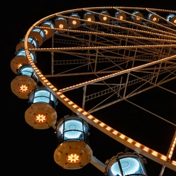 Kölner Riesenrad Detailreiche Aufnahme eines beleuchteten Riesenrads bei Nacht, das mit warmen, goldenen Lichtern in die Dunkelheit strahlt.