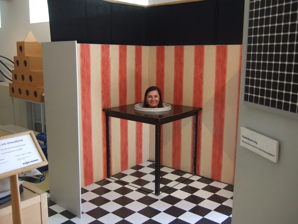 Phänomenta Bremerhaven Frau steckt scheinbar als optische Täuschung mit dem Kopf in einem Tisch in der Phänomenta Bremerhaven