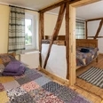 _PHM0003.jpg Zwei rustikale Schlafzimmer mit Holzbalken, Patchwork-Bettdecken und einem Fenster, das Licht hereinlässt.