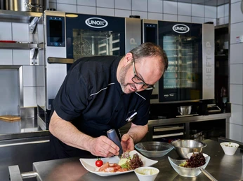 Der Gastgeber beim Anrichten in der Küche