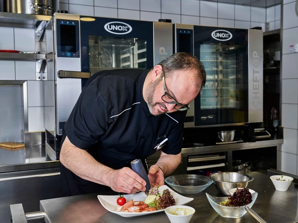 Der Gastgeber beim Anrichten in der Küche