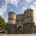 Hahnentorburg Das Bild zeigt das historische Hahnentor in Köln, eine massive Steinfestung mit zwei Rundtürmen unter blauem Himmel.The picture shows the historic Hahnentor in Cologne, a massive stone fortress with two round towers under a blue sky.