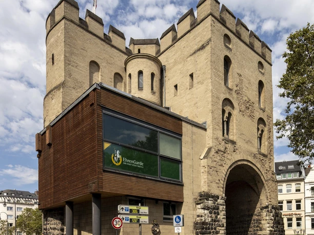 Hahnentorburg Das Hahnentor in Köln, ein mittelalterliches Stadttor aus hellem Sandstein mit drei Türmen, unter blauem Himmel.