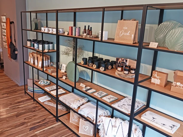 Langes Regal mit hübsch dekorierter Ware: Textilien, Kerzen und vieles mehr