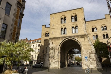 Eigelsteintorburg The picture shows the impressive Eigelsteintorburg in Cologne, a medieval gate castle in sandstone construction with three storeys, arches and historical details. It is surrounded by houses and shows a typical urban Cologne street scene.