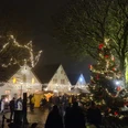 Weihnachtsmarkt Greetsiel Zu sehen ist der Blick auf den Weihnachtsmarkt bei Dunkelheit und mit Lichterketten. Vorne steht eine große geschmückte Weihnachtstanne. You can see the view of the Christmas market in the dark with fairy lights. In front is a large decorated Christmas tree.Du kan se udsigten til julemarkedet i mørket med lyskæder. Foran står et stort pyntet juletræ.Je kunt het uitzicht op de kerstmarkt zien in het donker met feeërieke lichtjes. Aan de voorkant staat een grote versierde kerstboom.