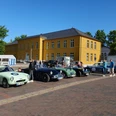 Rallye_Oldtimer.jpg Mehrere Oldtimer stehen vor dem Rathaus auf dem Parkplatz. Menschen schauen sie interessiert an