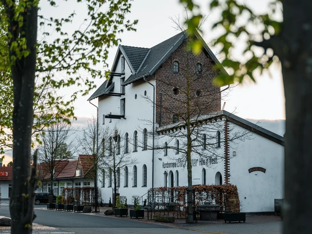 Alte Brennerei Hille Die Alte Brennerei Hille, ein historisches Gebäude mit Backstein und modernen Elementen im Grünen.