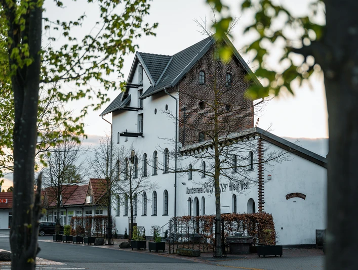 Alte Brennerei Hille Die Alte Brennerei Hille, ein historisches Gebäude mit Backstein und modernen Elementen im Grünen.