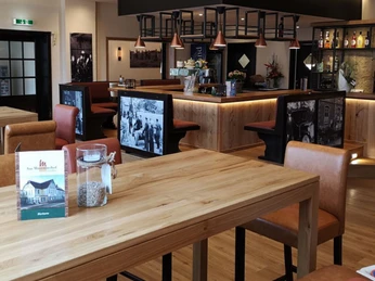 Modernes Restaurantinnendesign, Holzmöbel, beige und braune Details, beleuchtete Bar im Hintergrund.