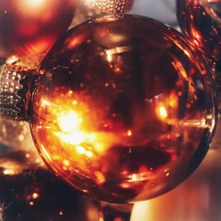 Glänzende Weihnachtskugel in warmen Goldtönen reflektiert stimmungsvoll das Kerzenlicht.