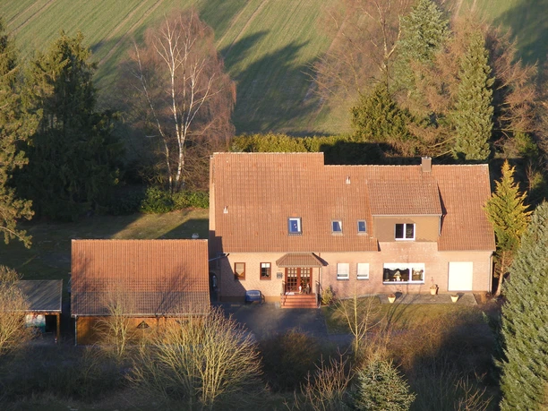 Ferienwohnung Niebaum Haus Großes Backsteinhaus mit Satteldach und Anbau, umgeben von Bäumen und Feldern in ländlicher Umgebung.